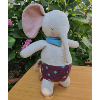 Ava & Yves Kuschelelefant aus Bio-Strick mit rosa Ohren, blauem Schal und gepunkteter Hose.