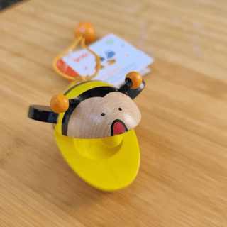 Goki Bienen-Kastagnette aus Holz, gelb mit schwarzen Streifen und orangefarbenen Fühlern, auf Holztisch.