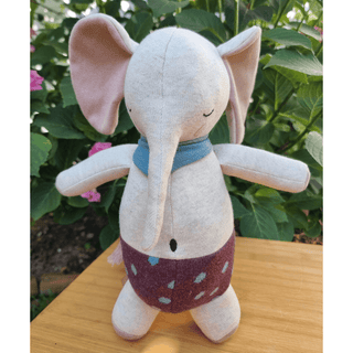 Ava & Yves Kuschelelefant aus Bio-Strick, beige mit blauem Halstuch und gemusterter Hose.