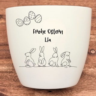 Weißer Blumentopf mit Ostermotiv: Ostereier und vier Hasen. Aufschrift "Frohe Ostern Lia". Ostergeschenk von Natur Macher.