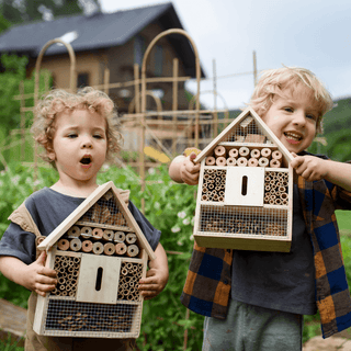 Zwei Kinder präsentieren stolz ihre selbstgebauten Insektenhotels von Naturmacher. Die Insektenhotels aus Holz und Bambus ...