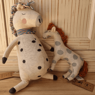 Ava&Yves lustiges Kuscheltier Rainbow Horse, gestrickt, beige mit schwarzen Punkten und buntem Schal, neben kleinerem, bla...