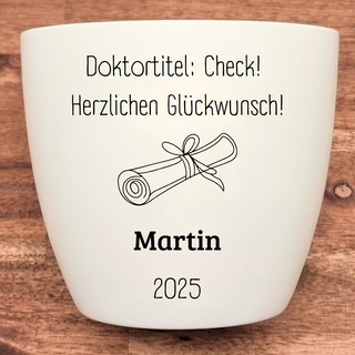 Weißer Blumentopf mit Doktorhut-Motiv und Aufschrift "Doktortitel: Check! Herzlichen Glückwunsch! Martin 2025". Abschlussg...