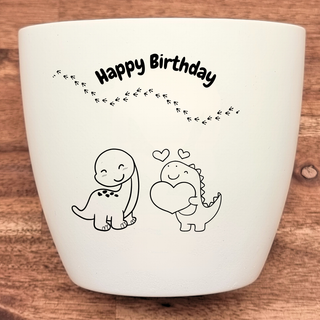 Weißer Blumentopf mit "Happy Birthday" und zwei Dinosauriern, einer hält ein Herz. Geburtstagsgeschenk von Natur Macher.