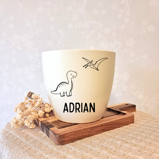 Weißer Blumentopf mit Dinosaurier-Motiv und dem Namen "Adrian", ideal für junge Dinosaurier-Fans.