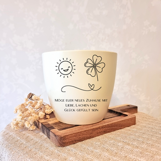 Beigener Blumentopf mit Sonne, Kleeblatt und "Möge euer neues Zuhause mit Liebe, Lachen und Glück gefüllt sein". Einzugsge...