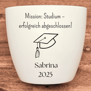 Weißer Blumentopf mit "Mission: Studium - erfolgreich abgeschlossen!",  Absolventenhut-Symbol und "Sabrina 2025". Abschlus...