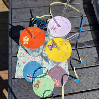 Bunte Glasabdeckungen mit Tiermotiven und Strohhalmlöchern, personalisiert mit Namen. Bastelvorlage von Naturmacher.