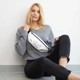 Frau mit grauem Pullover trägt weiße Bensheim Gürteltasche von Naturmacher, sitzt lässig auf Boden.