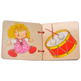 Goki Holzbilderbuch, geöffnet, zeigt Puppe und Trommel. Für Kleinkinder.