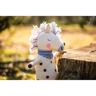 Kuscheltier Rainbow Horse von ava&yves aus Bio-Strick, weiß mit schwarzen Punkten und buntem Schal.