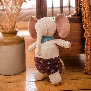 Kuscheliger Elefant aus Bio-Strick von ava&yves mit Schal und gepunkteter Hose. Stehend auf Holzboden.